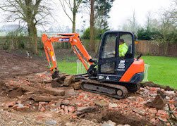 Mini excavator working near rubble.